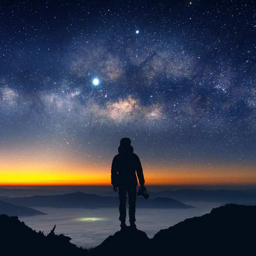 Immagine della silhouette di un fotografo di fronte a un cielo stellato, con il tramonto